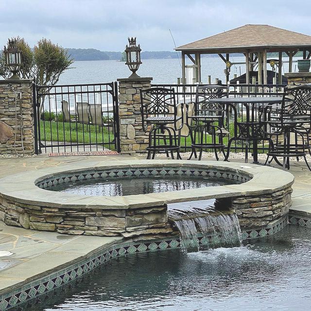 inground waterfall with patio chairs over looking the water